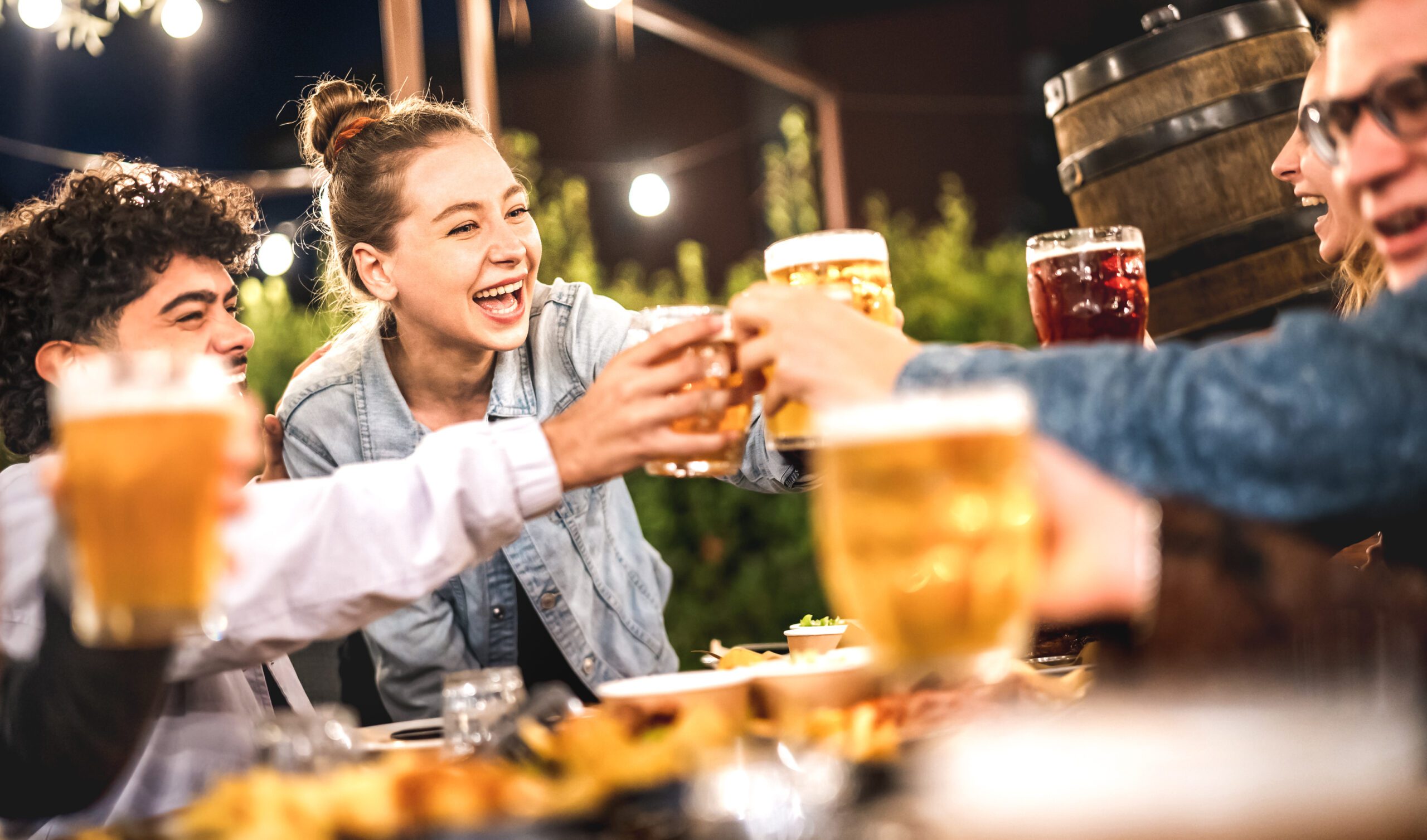 Happy friends toasting beer at brewery restaurant patio – Life style and beverage concept with young people having fun together out side at patio garden by night